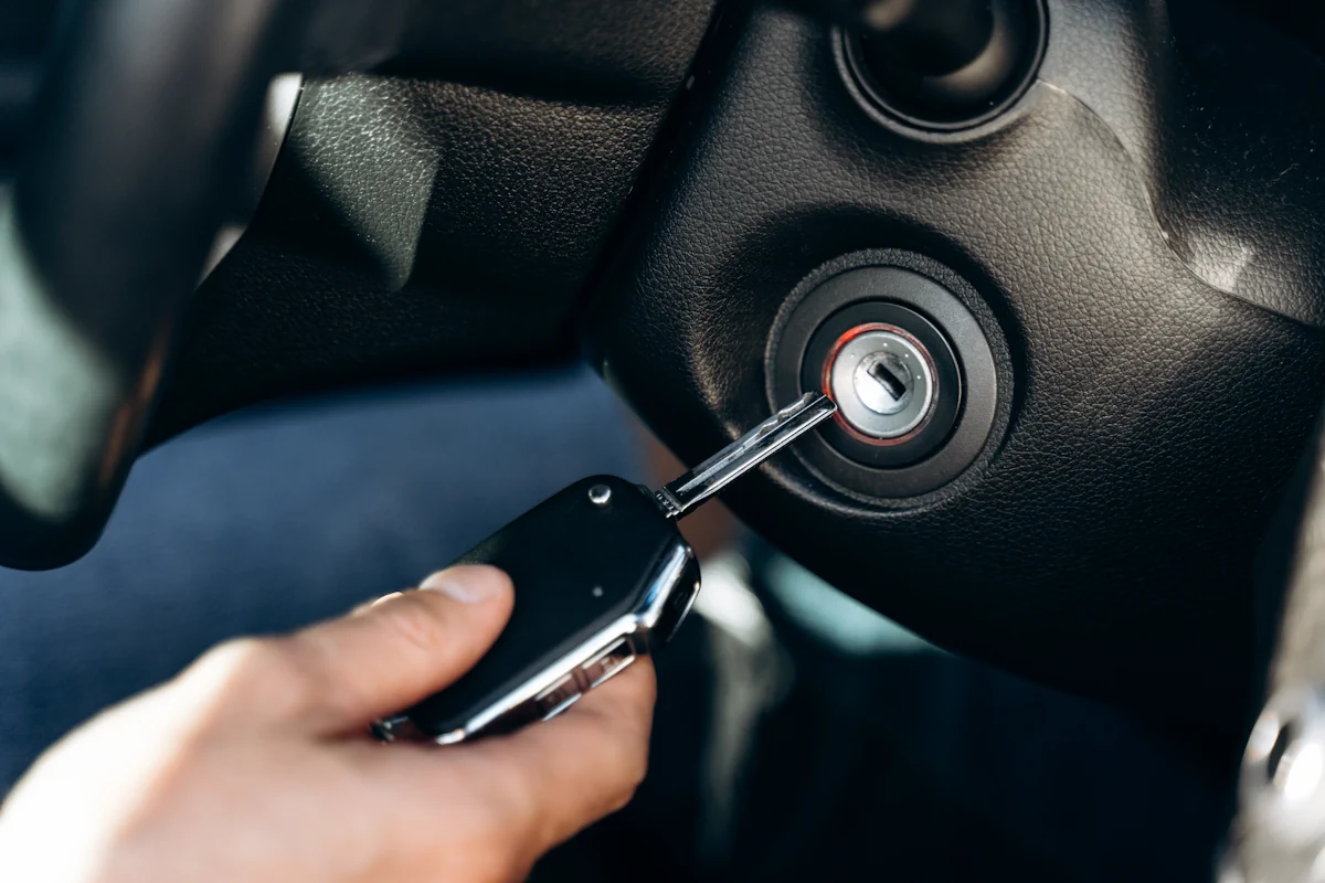 Une personne qui fait entrée une clé dans le contact d'une voiture