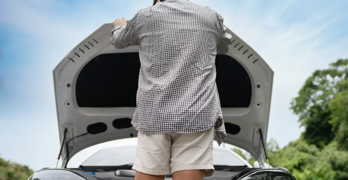 Un homme qui regarde sous le capot d'une voiture