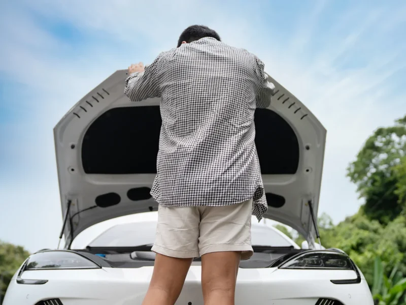 Un homme qui regarde sous le capot d'une voiture