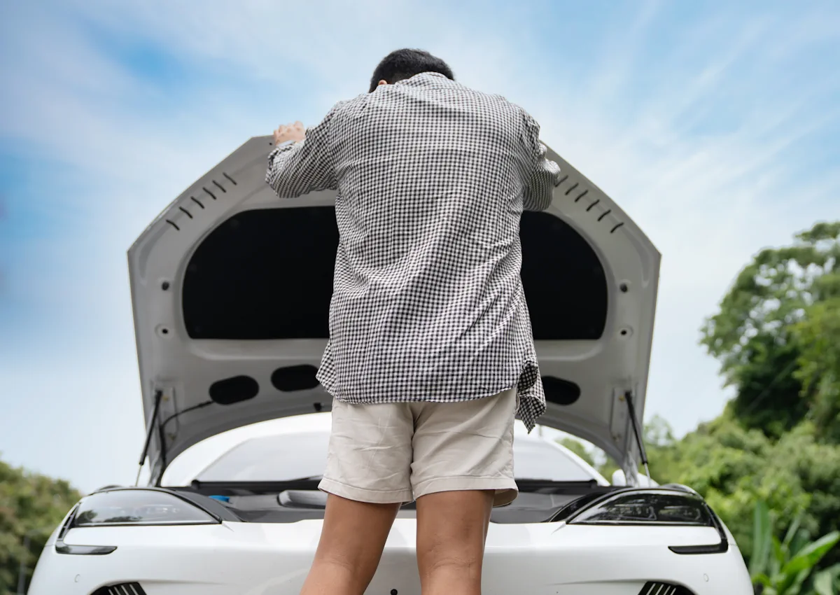 Un homme qui regarde sous le capot d'une voiture