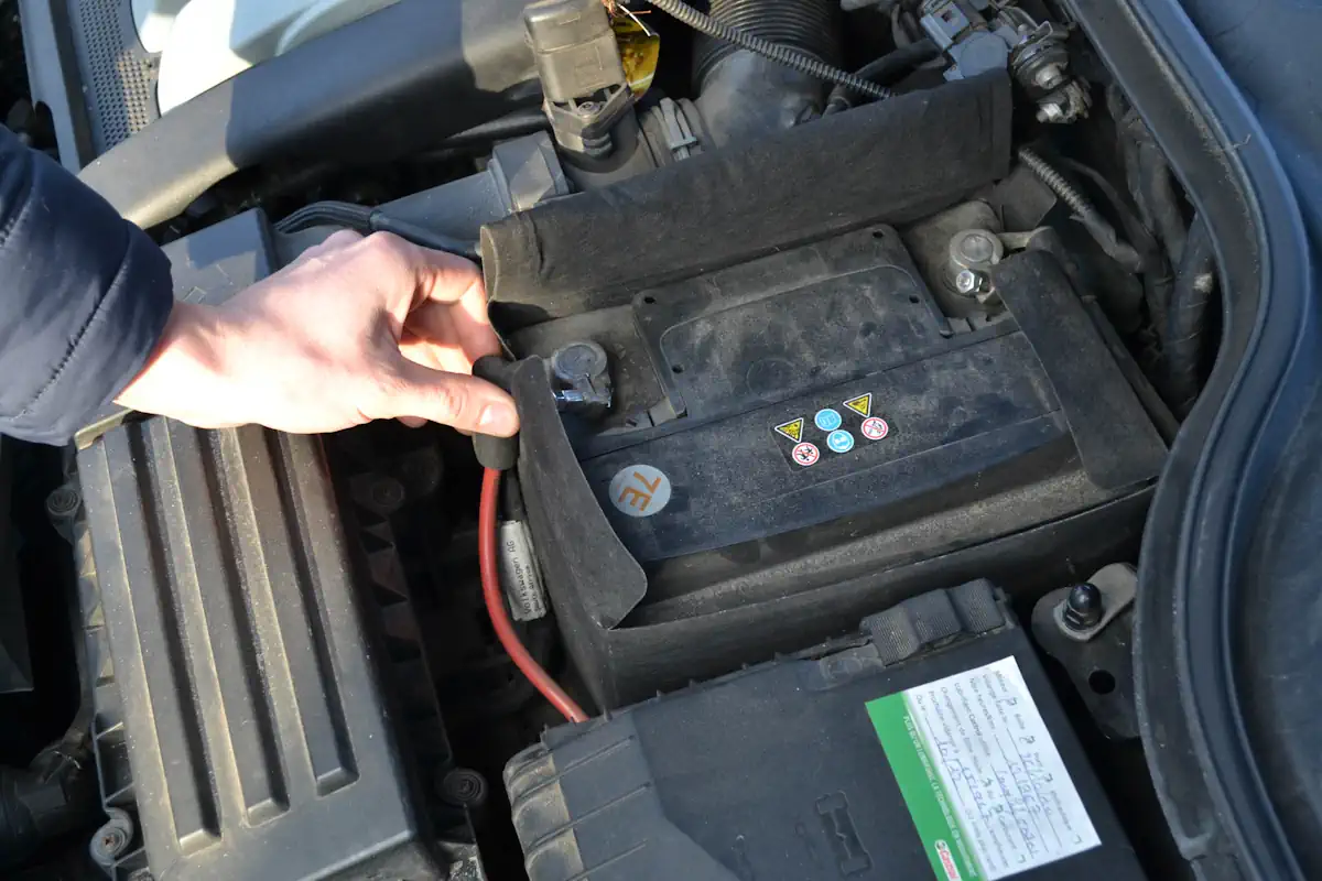 Une personne qui débranche la batterie d'une voiture