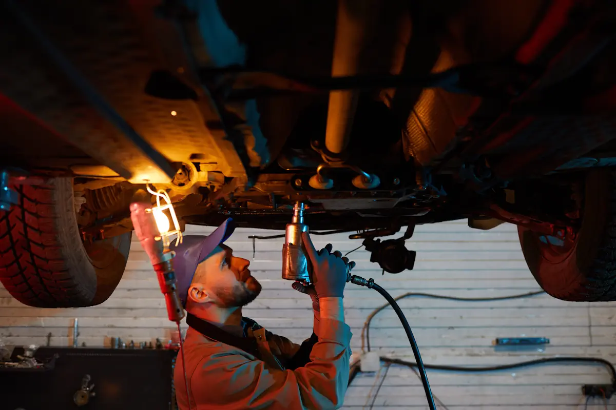 Un homme qui utilise un décapeur thermique sous une voiture