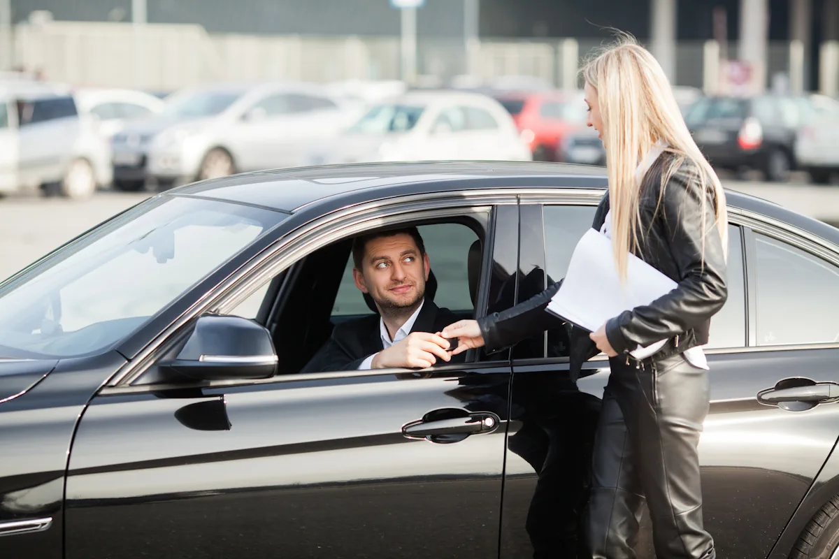 Une mandataire auto qui tend les clefs à un homme dans une voiture