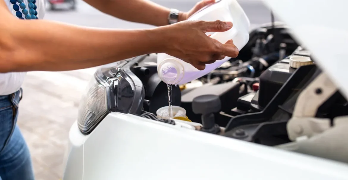 Une personne qui verse du liquide de refroidissement dans une voiture après une purge
