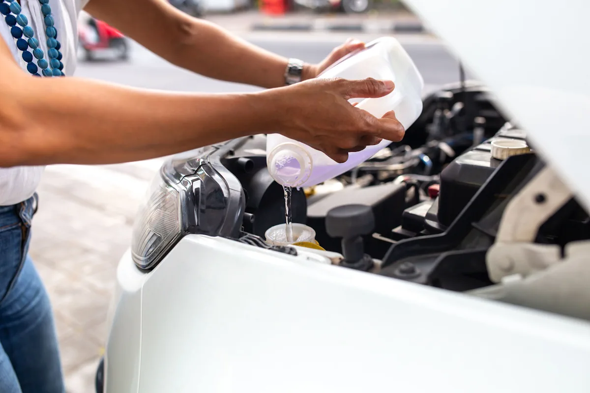 Une personne qui verse du liquide de refroidissement dans une voiture après une purge